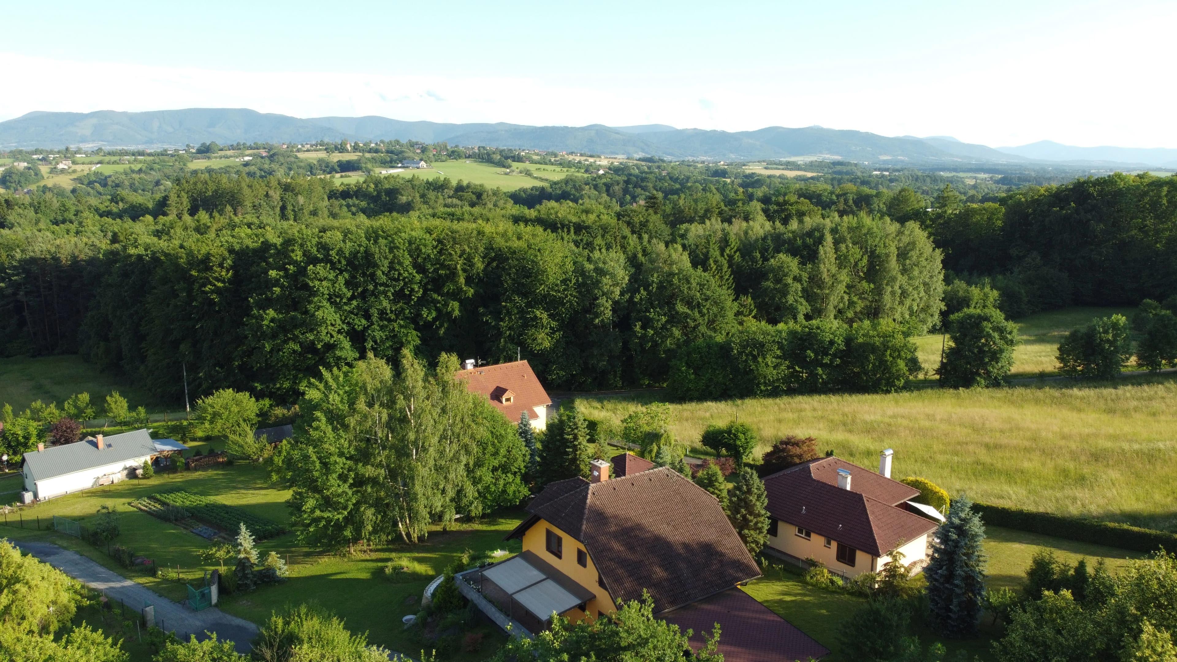 Fotka hezkého rodinného domu s horami v pozadí.